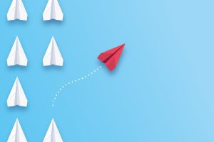 Concept bold thinking—individual red paper plane flies in different direction in contrast to crowd of ordinary white planes