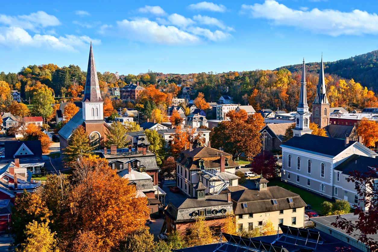 Aerial view of the capital city of Montpelier, Vermont. Leaves in bright fall colors, and three church spires among the small-city houses and building of brick and clapboard.